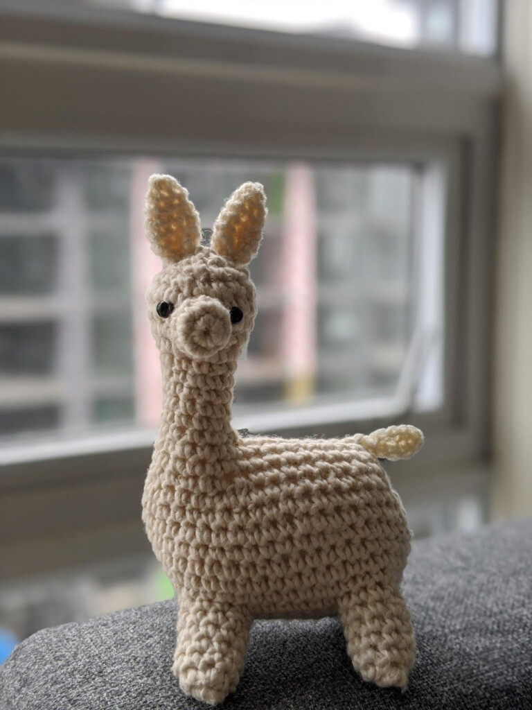 A Small Crocheted Llama Sitting On Top Of A Couch Next To A Window - Alpaca Crochet Blanket Pattern